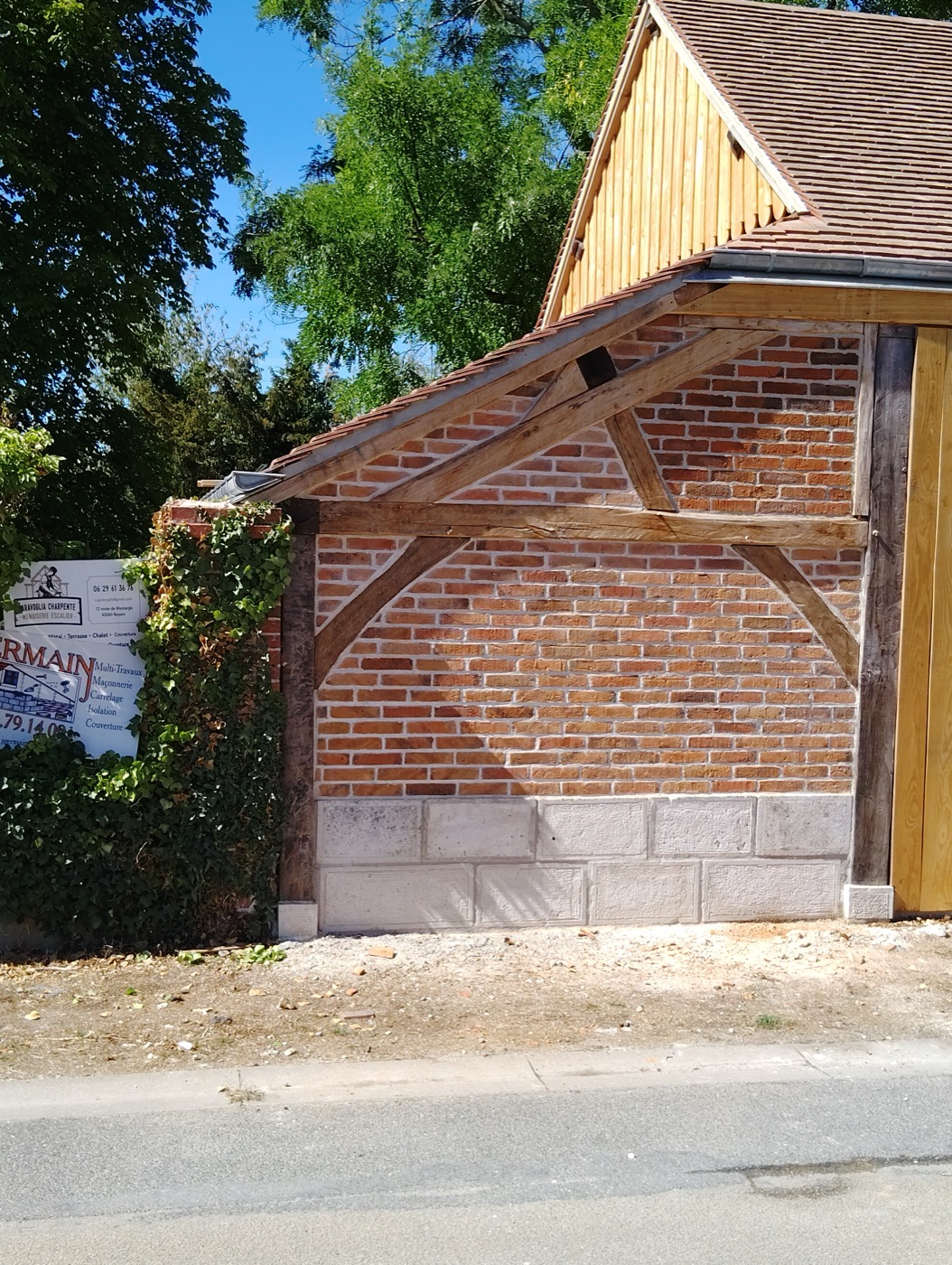 Mur en brique terminé sous l'arc en bois, soubassement en pierre